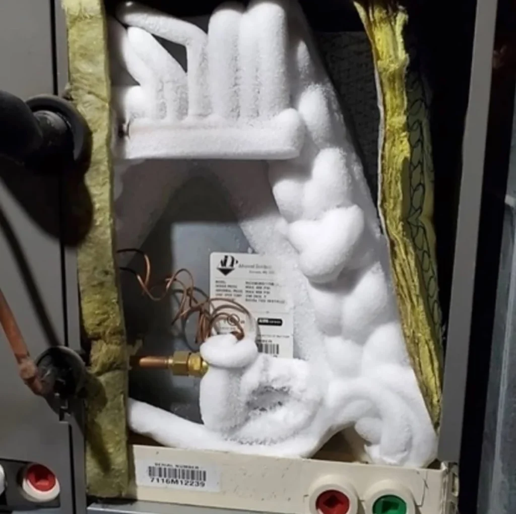 Evaporator coil fins bent reducing airflow in Raceland, LA: close-up of ice buildup on indoor HVAC components