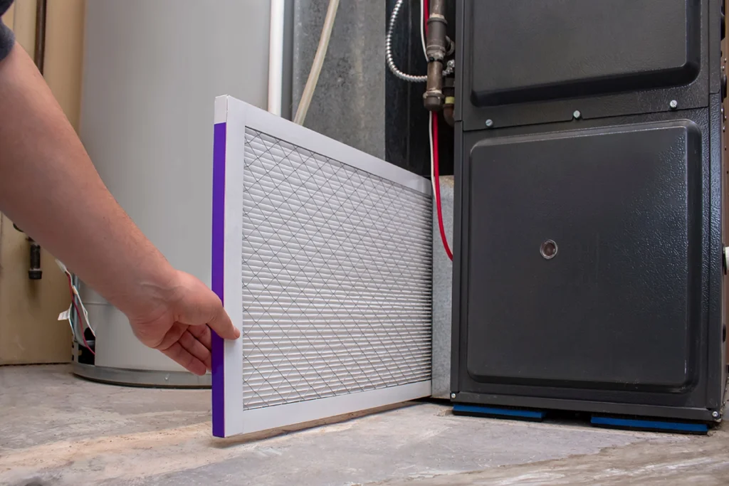 Furnace blower capacitor failing causing weak airflow in Morgan City, LA: hand placing a pleated HVAC air filter