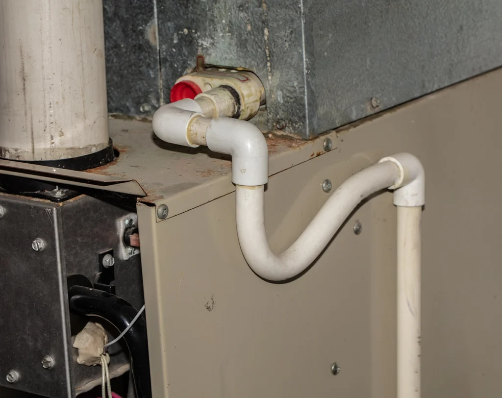 Furnace ignitor clicking but not lighting in Thibodaux LA: close-up of a high-efficiency furnace with PVC condensate drain