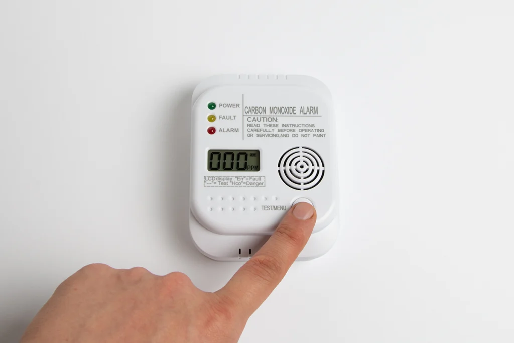 Heat exchanger cracked leaking carbon monoxide in Raceland, LA: hand pressing the test button on a wall-mounted carbon