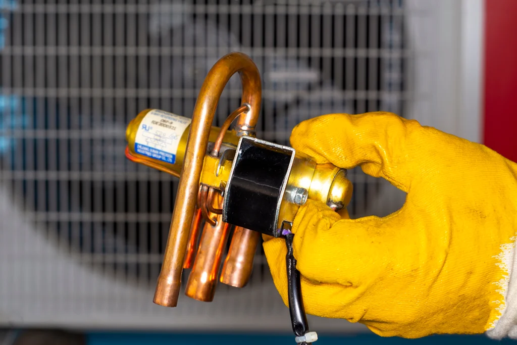 Reversing valve stuck preventing heat mode in Morgan City, LA: close-up of a thermal expansion valve (TXV) assembly being